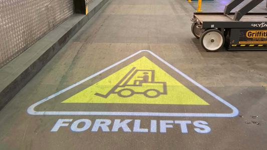 Yellow forklift projected sign on a warehouse floor.