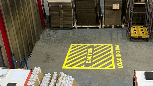 Yellow loading bay safety sign projected onto a warehouse floor using LED gobo projectors.