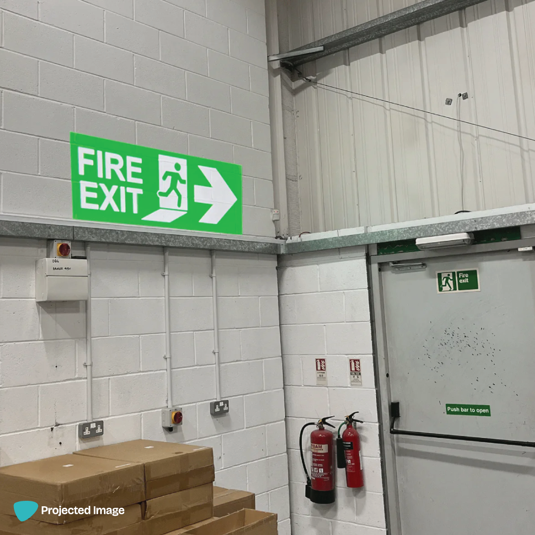 Projected fire exit sign on a warehouse wall.