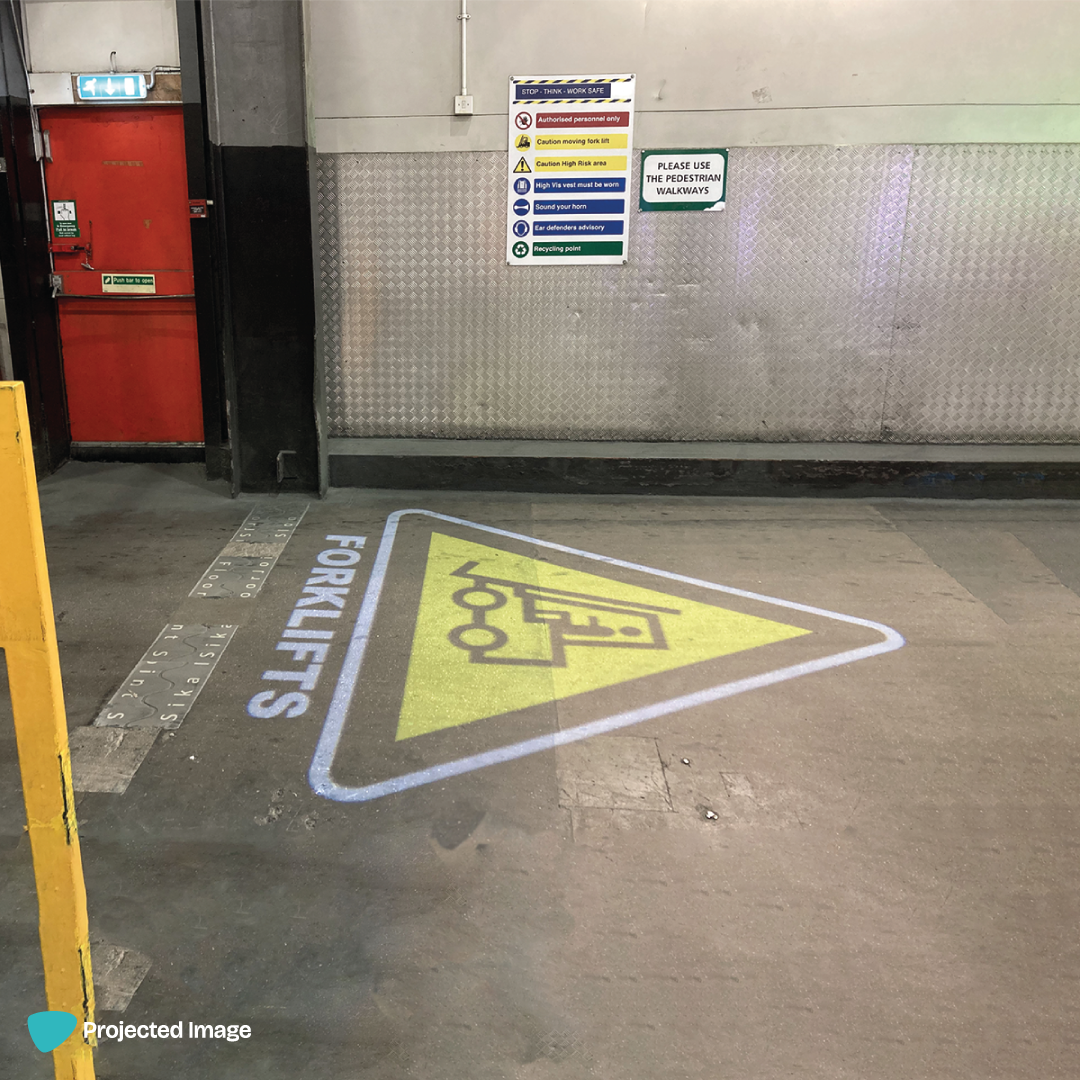 Forklift safety sign projected onto a warehouse floor.