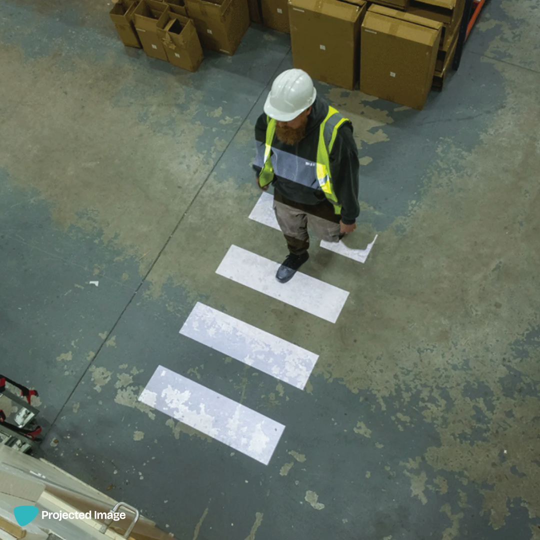 Projected zebra crossing sign on a warehouse floor.