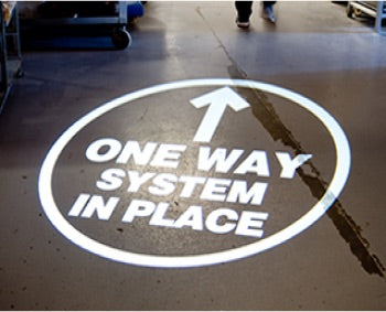 Social distancing one way in place projected signage.