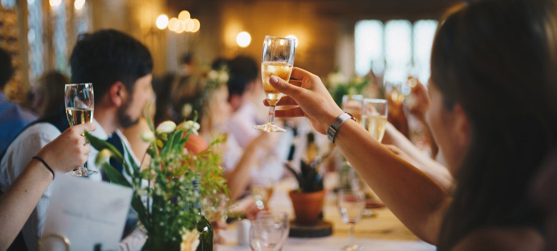 Hand raising a toast with a champagne flute at a wedding.