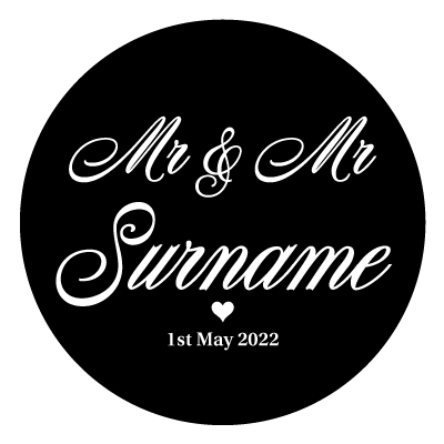 White "Mr & Mr Surname" text with a small white heart below. Underneath the small heart is the text "1st May 2022" in white. All on a black circle.