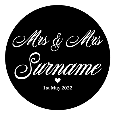 White "Mrs & Mrs Surname" text with a small white heart below. Underneath the small heart is the text "1st May 2022" in white. All on a black circle.