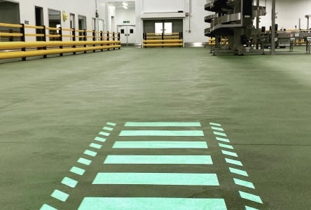 Zebra crossing sign projected onto a warehouse floor.