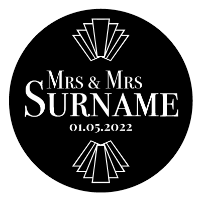 "Mrs & Mrs Surname" text with "01.05.2022" underneath. Above and below this text is an art deco style pattern. All white on a black circle.